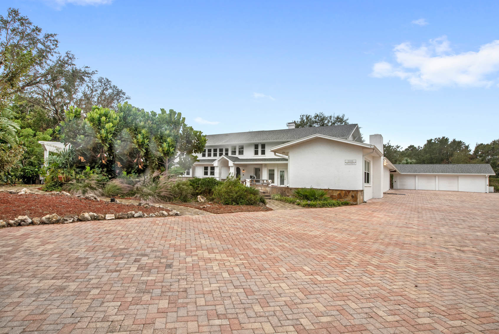front of two story white hom with brick driveway